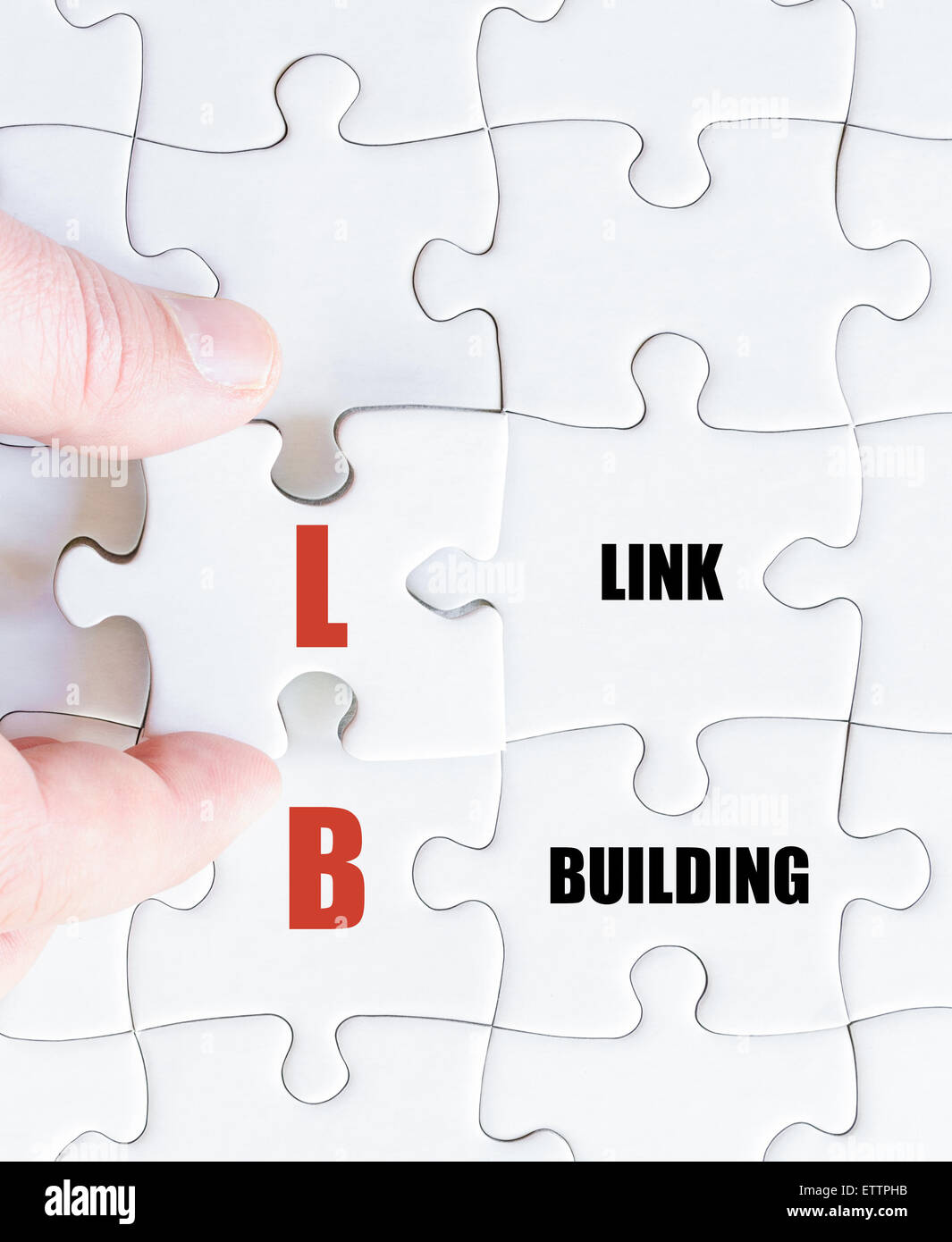 La mano di un uomo di affari di completare il puzzle con l'ultimo pezzo mancante.Concetto di immagine di Business acronimo LB come Link Building Foto Stock