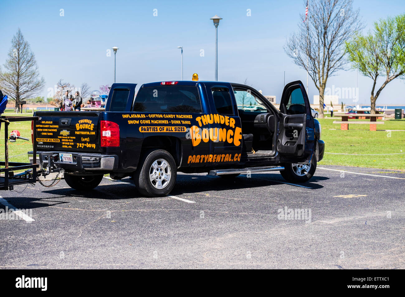 Un business carrello con la scrittura di pubblicità case di bounce,noleggi,e partito acruements è parcheggiata con le porte aperte a un parco pubblico negli Stati Uniti. Foto Stock