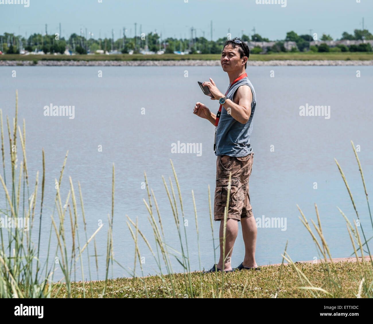 Cinquant'anni di vecchio uomo asiatico scatta foto con il suo telefono cellulare al Lago Hefner nella città di Oklahoma, Oklahoma, Stati Uniti d'America. Foto Stock