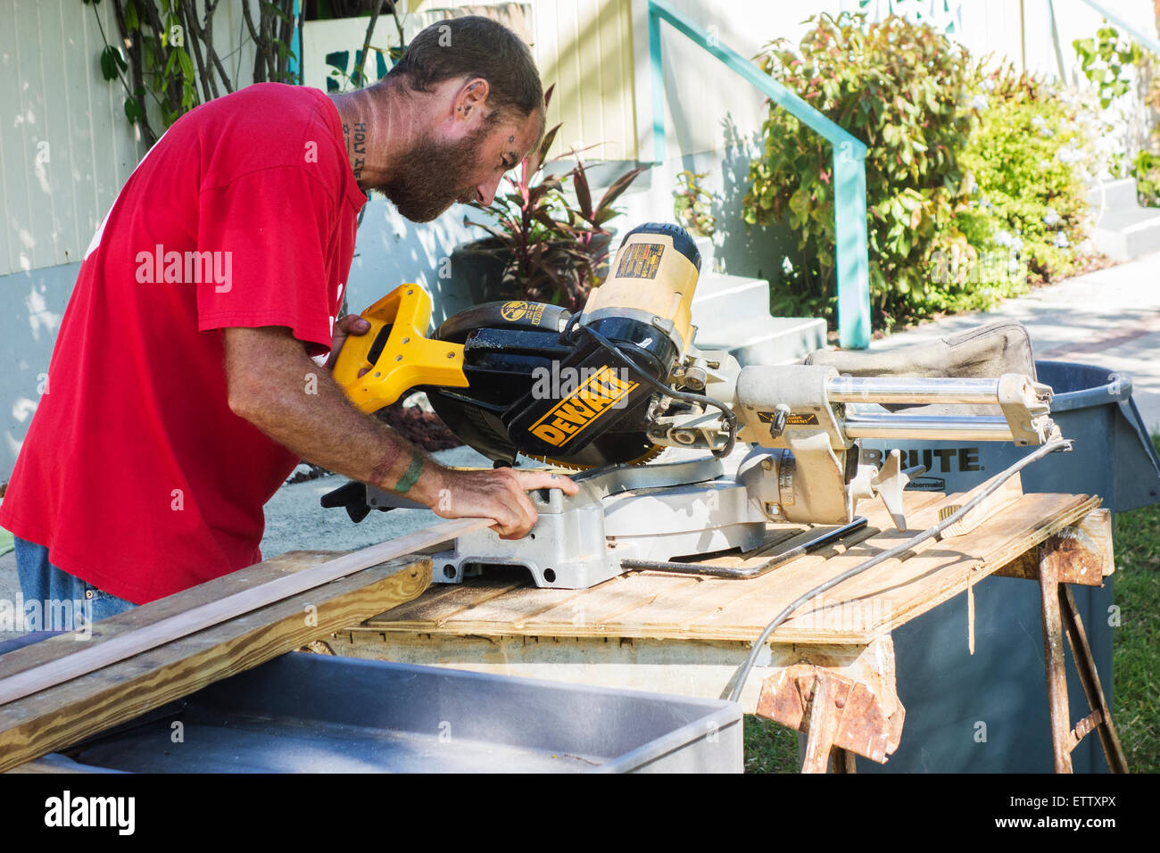Un uomo tatooed lavora con strumenti di potenza in un resort sulla spiaggia. St. Croix, U.S. Isole Vergini. Foto Stock