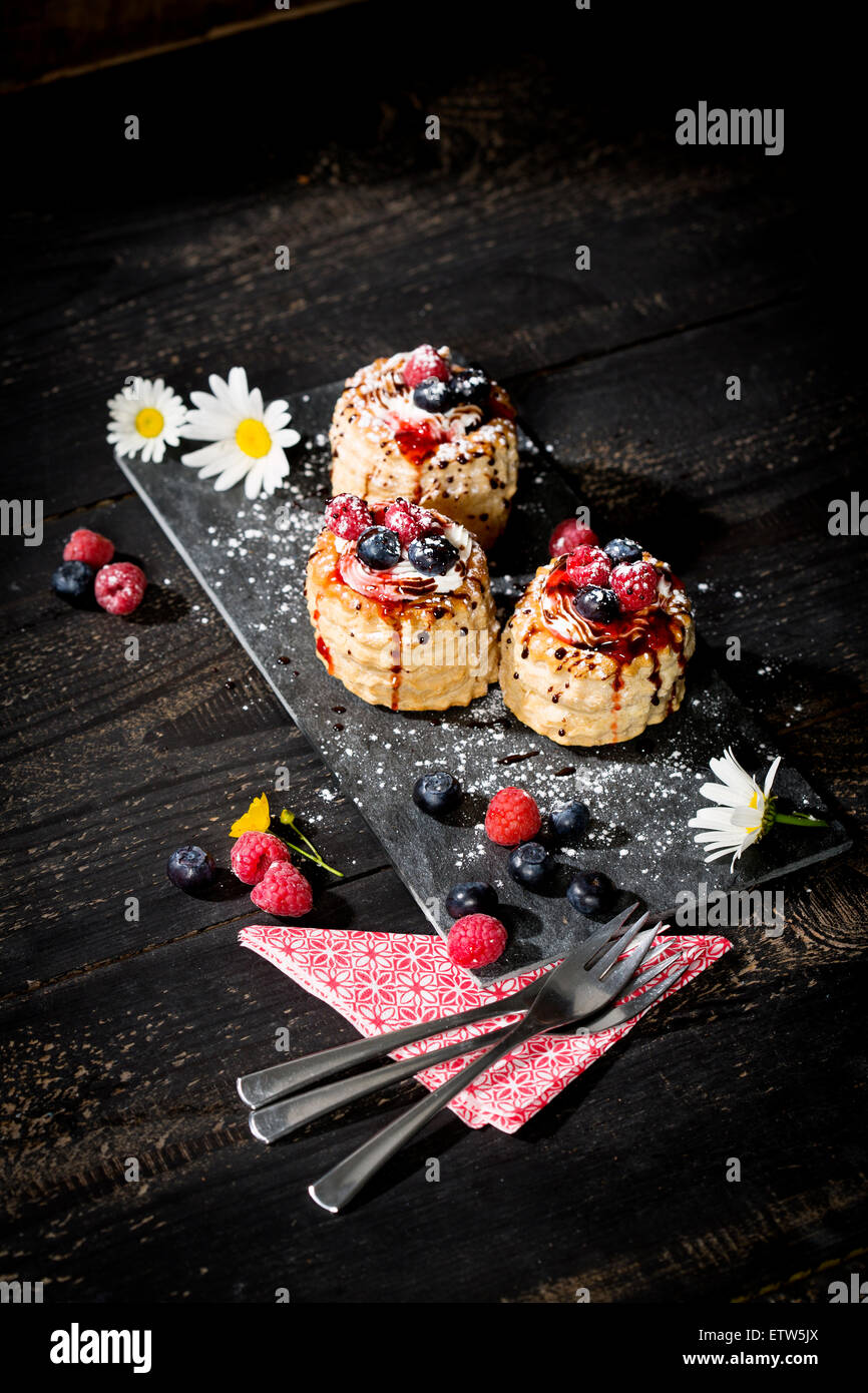 Filo pasticceria pasticcini riempiti con gelato alla vaniglia e panna guarnito con mirtilli e lamponi Foto Stock