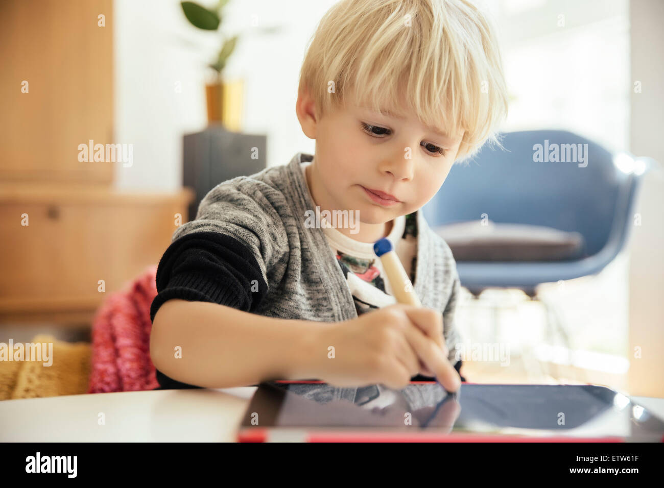 Ritratto di Little Boy disegno con una penna digitale sulla tavoletta digitale in casa Foto Stock