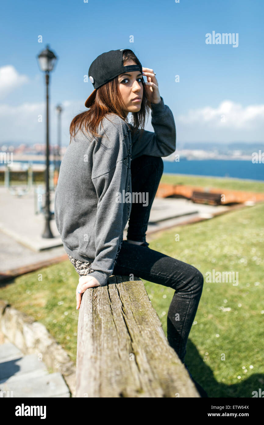 Spagna Gijon, giovane donna seduta su trave in legno Foto Stock