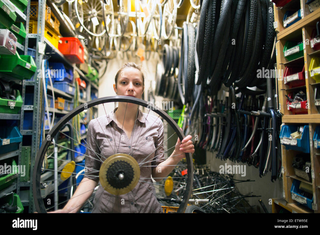 Giovane donna in un negozio di riparazione di biciclette contenimento del pneumatico Foto Stock