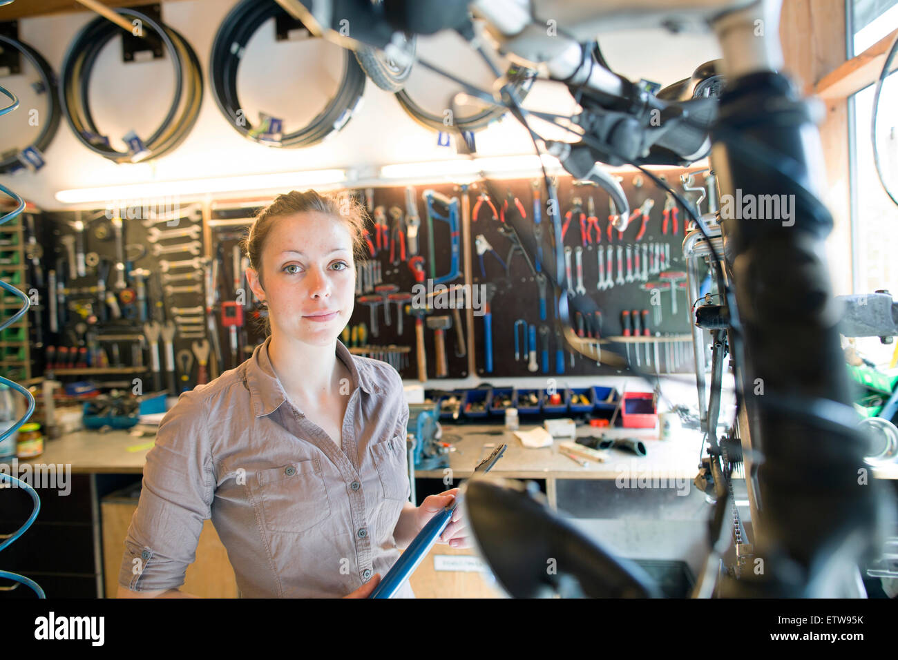 Giovane donna che lavora in un negozio di riparazione di biciclette Foto Stock