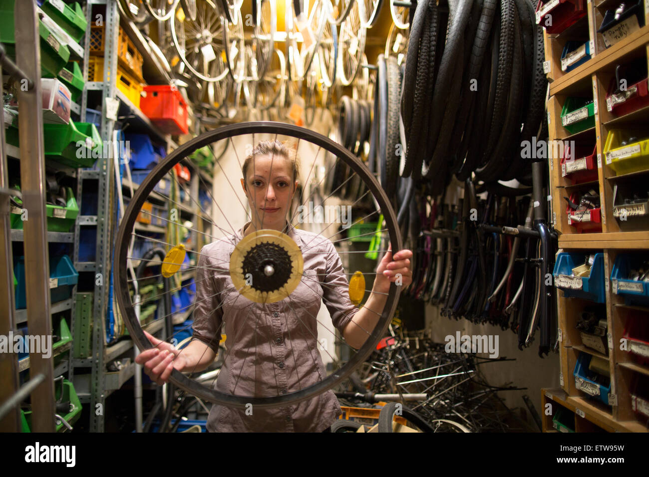 Giovane donna in un negozio di riparazione di biciclette contenimento del pneumatico Foto Stock