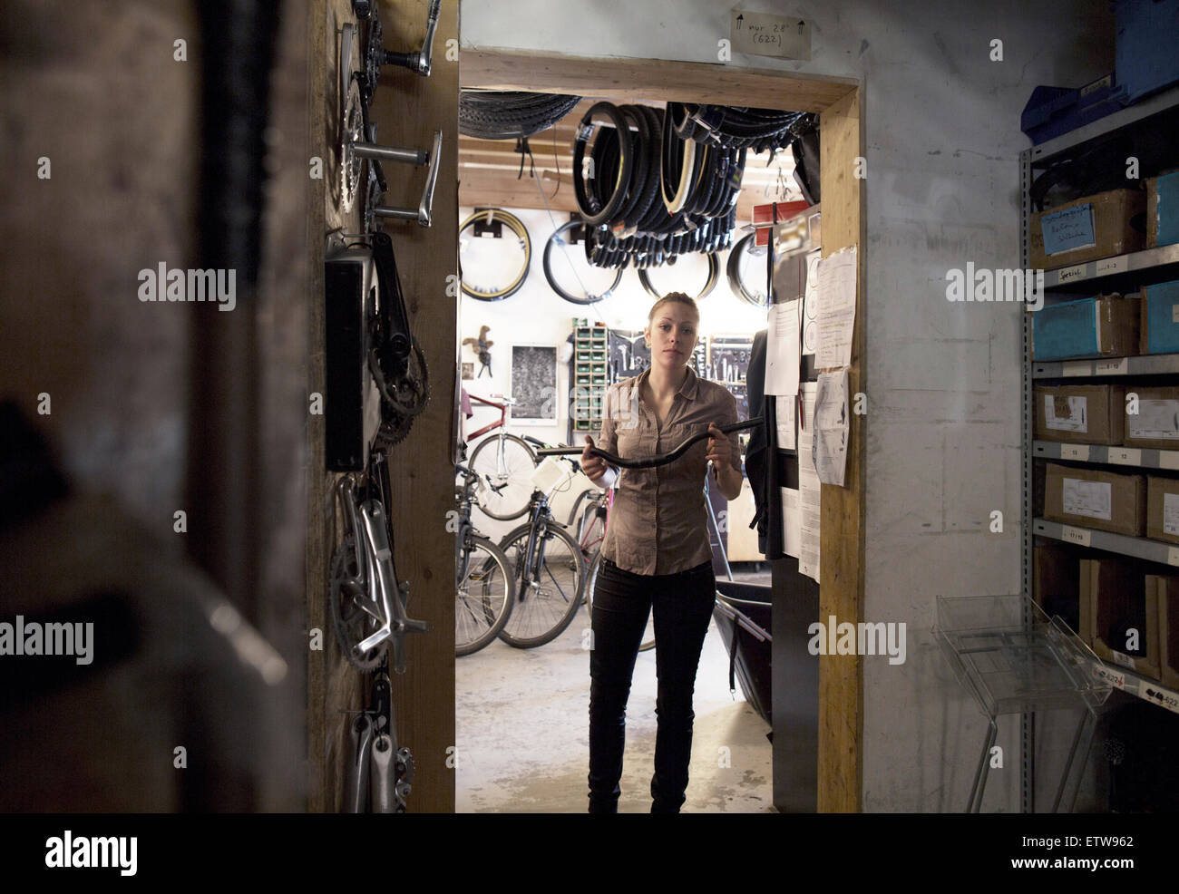 Giovane donna in un negozio di riparazione di biciclette holding manubrio Foto Stock