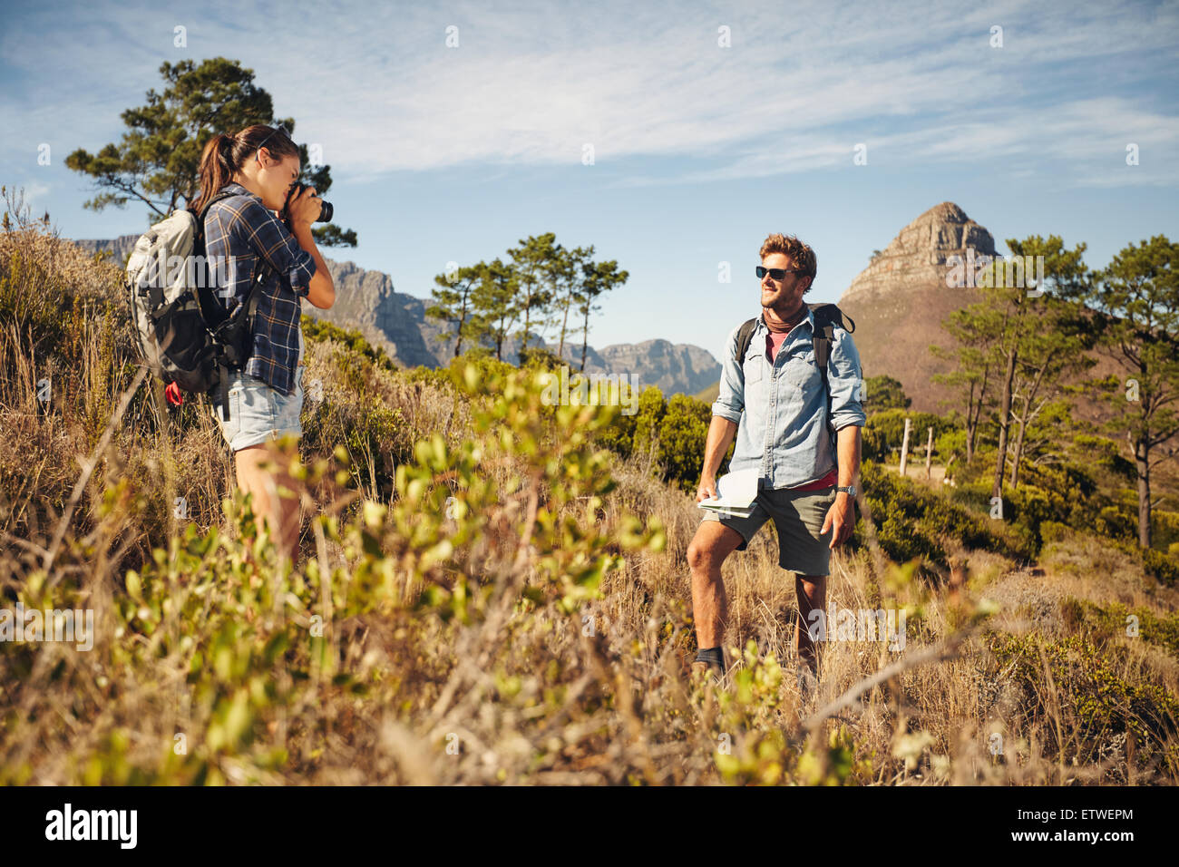 Giovane donna di scattare una foto del ragazzo in campagna durante il trekking durante le vacanze estive. Coppia giovane escursionismo. Foto Stock