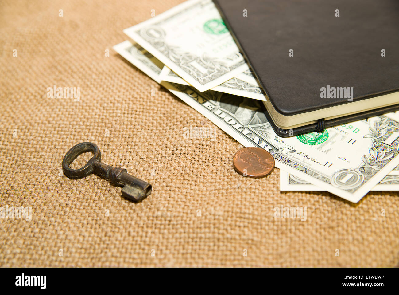 Notebook con un foglio bianco, chiave e denaro sul vecchio tessuto Foto Stock
