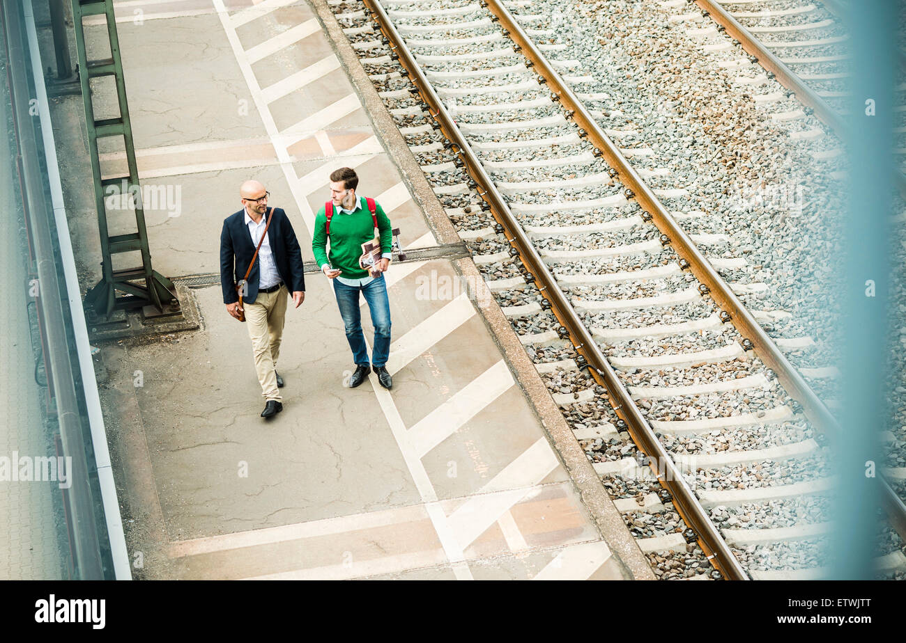 Due uomini a piedi sulla piattaforma ferroviaria Foto Stock