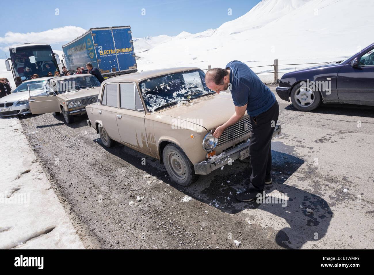 Pulizia del driver la sua Lada 1200 (VAZ 2101) auto in coda sul militare georgiano autostrada, montagne del Caucaso, Georgia Foto Stock