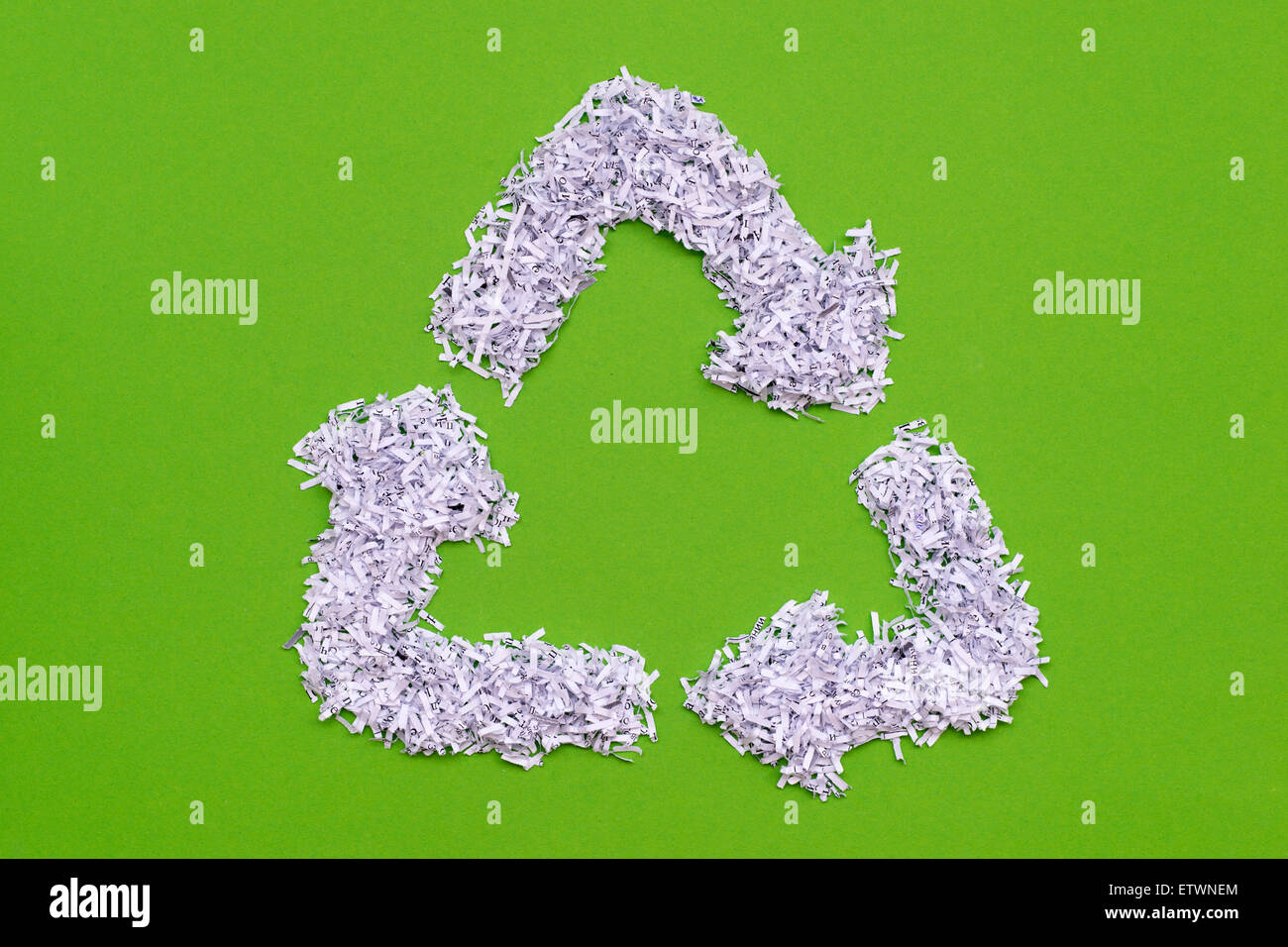 Simbolo di riciclaggio realizzato dal mucchio di shredded libro bianco su verde Foto Stock