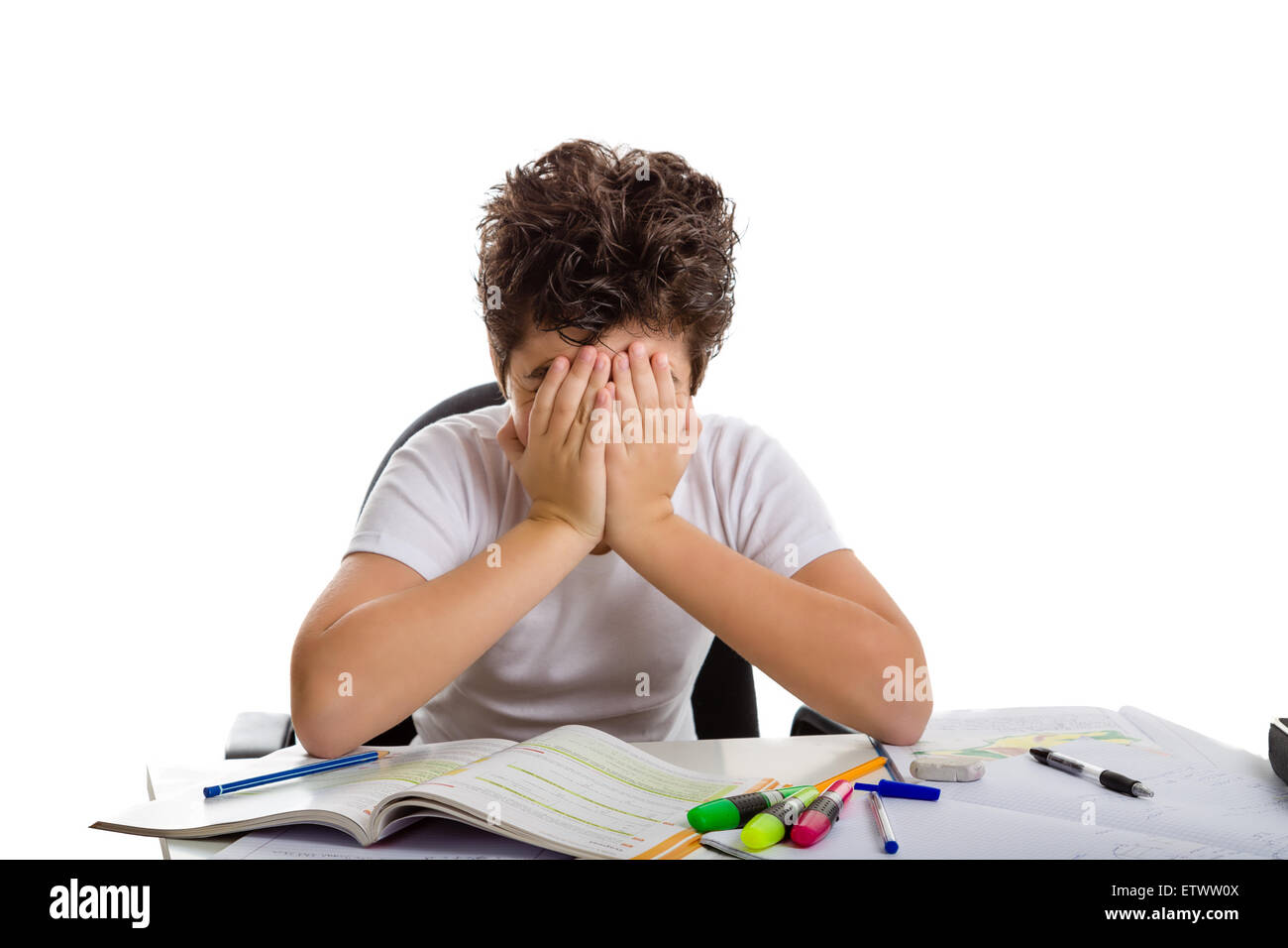 Stanco ragazzo nasconde il suo volto a fare il suo dovere: egli è seduto di fronte a libri,copybooks e matite Foto Stock