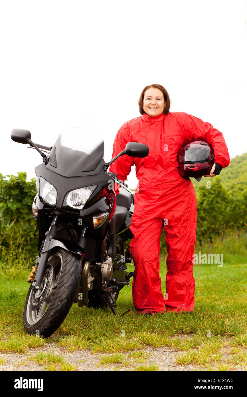 Motociclista mette sulla protezione dalla pioggia Foto Stock