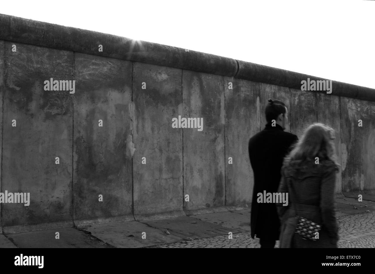 Berlino, Germania, gli uomini e le donne a piedi passato una parte del vecchio muro di confine Foto Stock