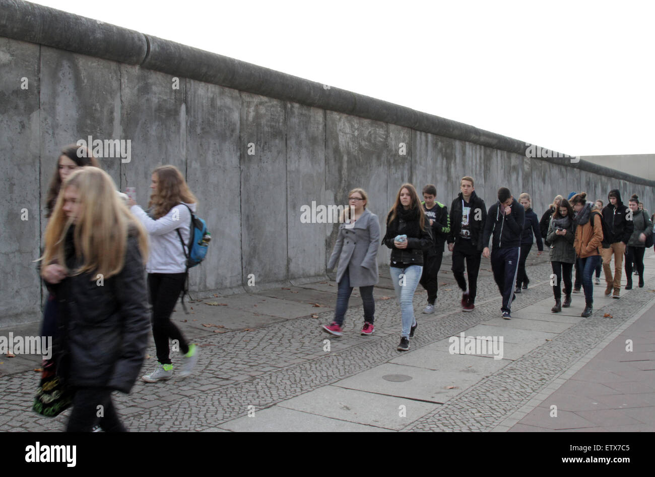 Berlino, Germania, gli adolescenti a piedi passato una parte del vecchio muro di confine Foto Stock