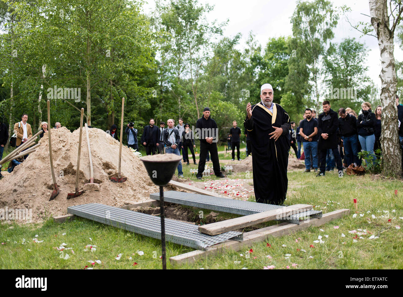 L Imam Abdallah Hajjir (C) prega sulla tomba di una donna dalla Siria morti nel Mare Mediterraneo nella sezione musulmana del cimitero Berlin-Gatow a Berlino, Germania, 16 giugno 2015. Il funerale è un'azione organizzata dagli attivisti con il "Centro di Bellezza politico, ' che protestano contro l'UE della politica in materia di profughi. La donna di superstiti che vivono in Germania e concordati per l'azione non erano presenti. Contrariamente agli attivisti dichiarazione", della donna e del bambino che ha anche annegati in volo, non saranno sepolti con lei. Secondo gli attivisti, erano entrambi a bordo di una nave Foto Stock