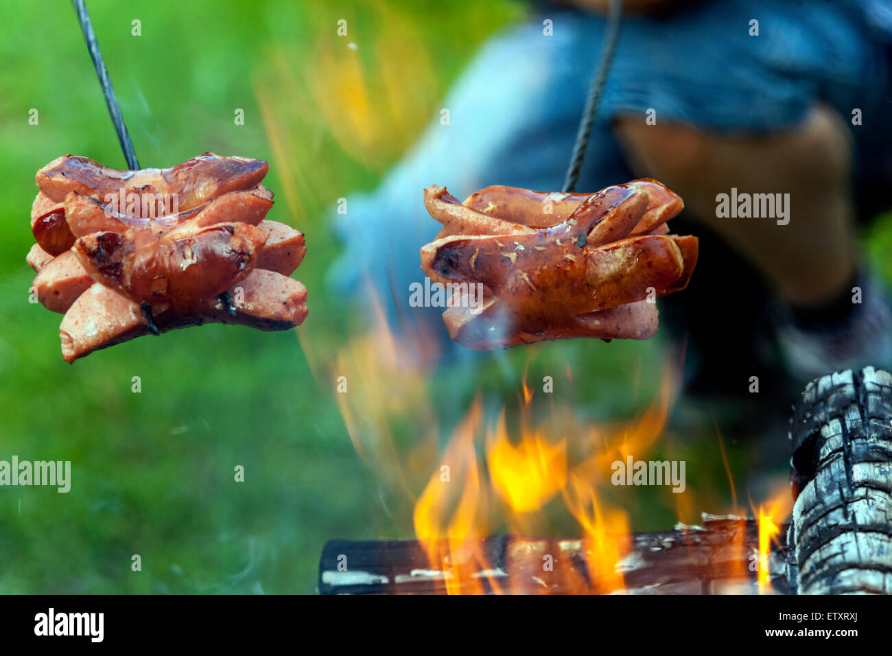 Salsicce sul bastone sopra il fuoco, festa falò giardino Foto Stock