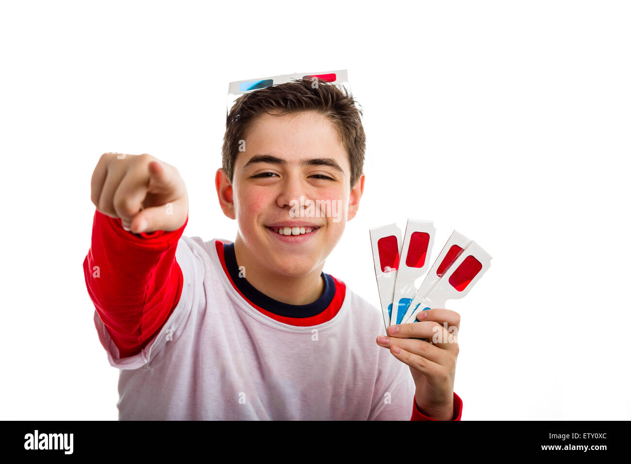 Un ragazzo caucasico sorrisi indossando un paio di cinema 3D occhiali di carta sulla sua testa con il rosso e il blu cielo lenti e contiene altre 4 quelli con mano sinistra rivolta al visualizzatore con la mano destra Foto Stock