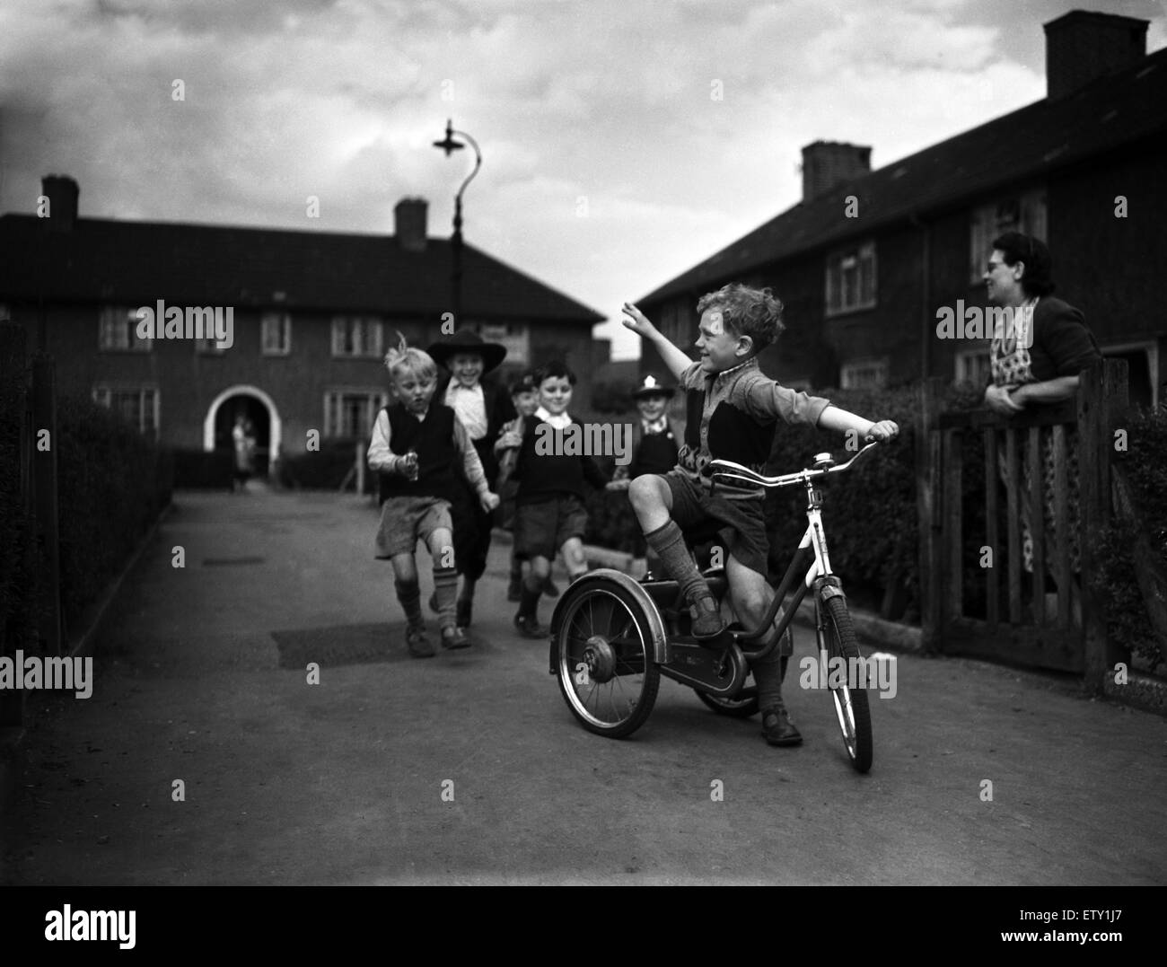 Ragazzi giocare su un consiglio estate come una delle loro madri guarda, Londra, 1955. Foto Stock