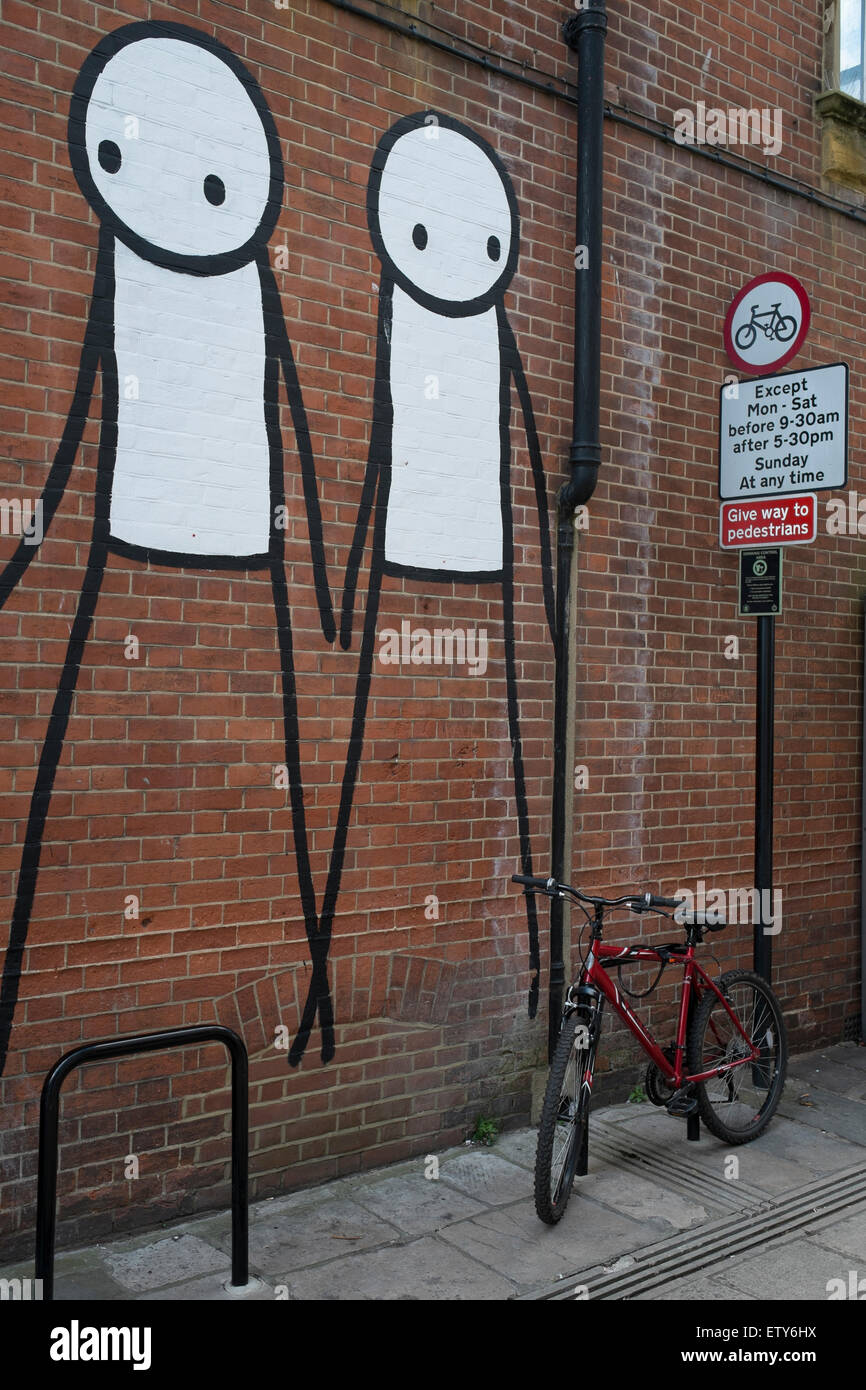 Stick gli uomini sono dipinti su una Londra muro di mattoni vicino a una bicicletta Foto Stock