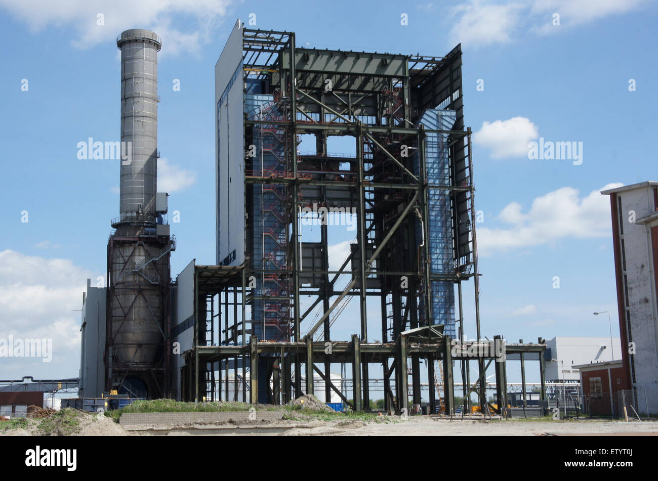 L'Hemwegcentrale Nuon è una centrale elettrica situata vicino ad un porto affollato, con varie navi come navi cisterna, navi portacontainer e rimorchiatori che navigano nel porto. Questa immagine cattura il diverso traffico marino in un affollato corso d'acqua utilizzato per il trasporto di merci e forniture di energia. Foto Stock