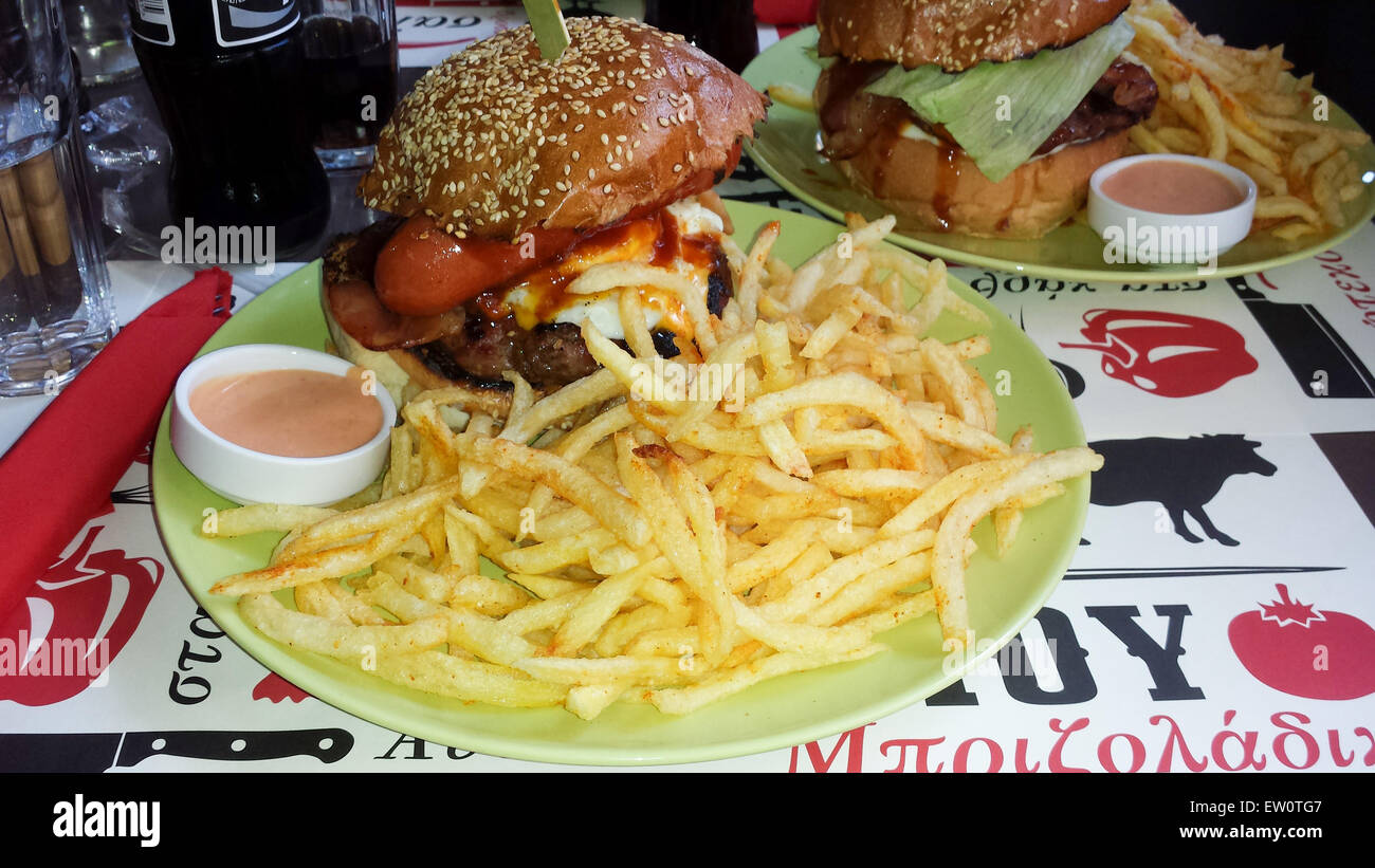 Vista di un enorme hamburger di burger, uova fritte, salsicce, salsa barbecue e la pancetta accompagnato da patate fritte e salsa. Foto Stock