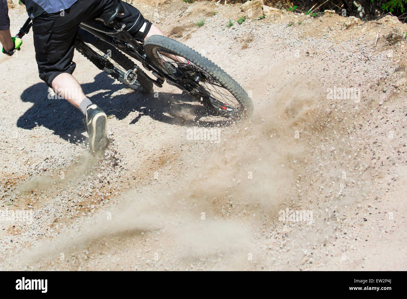 Versione non filtrata di mountain bike rider drifting attraverso una pendenza di gravità di una artificiale pista downhill. Spray di ghiaia verso l'alto Foto Stock
