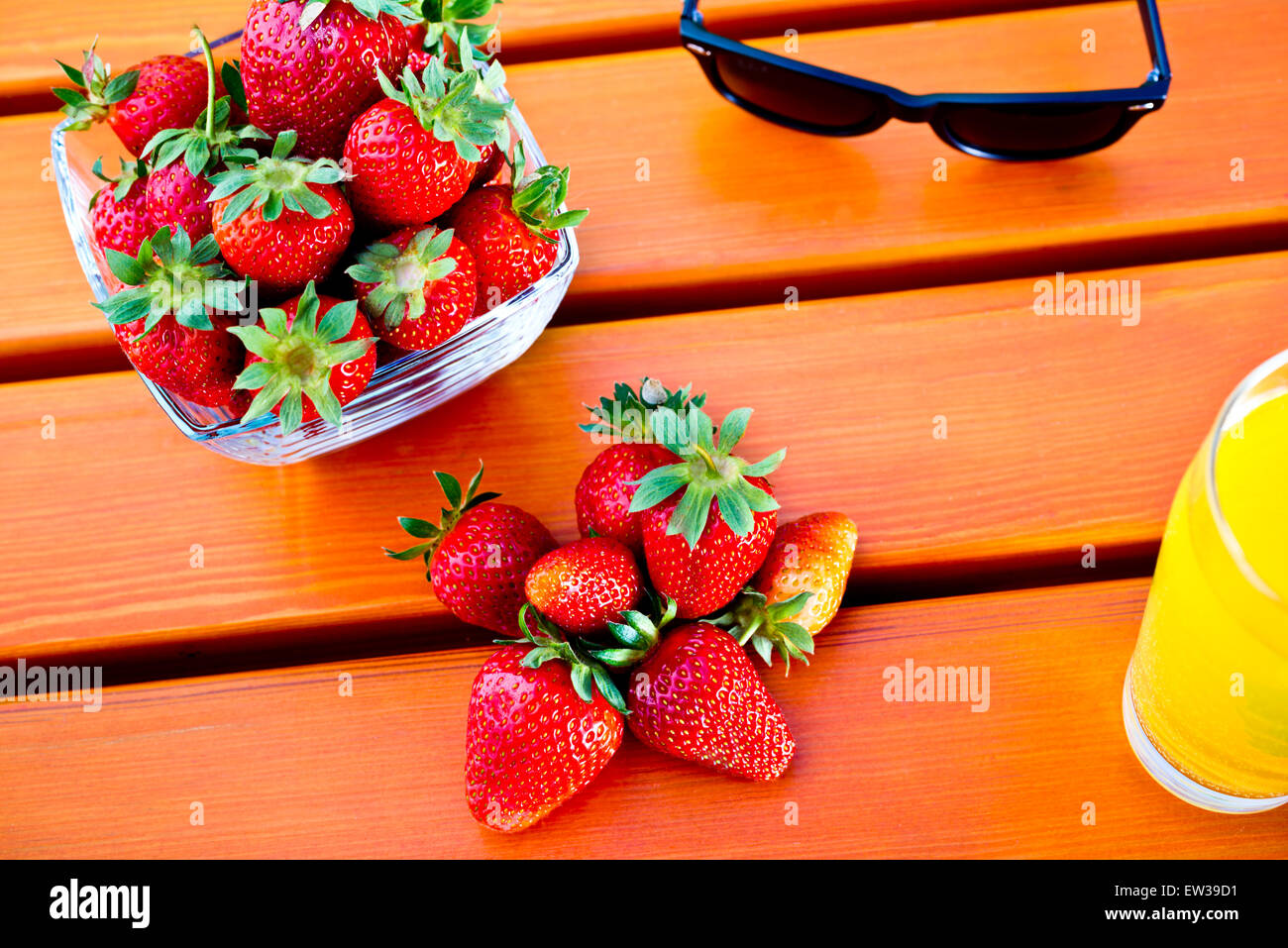 Fragola con occhiali da sole e succo di frutta sul tavolo in giardino,profondità di campo Foto Stock