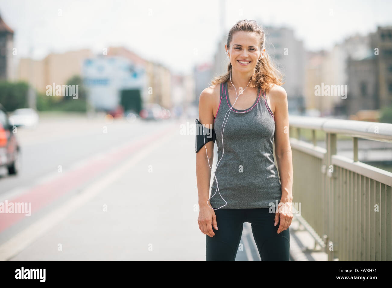 Una donna è sempre sorridente felicemente come ella si prende una pausa su un ponte. Ella è rilassato, felice, e montare, e godendo di allenamento in sun Foto Stock