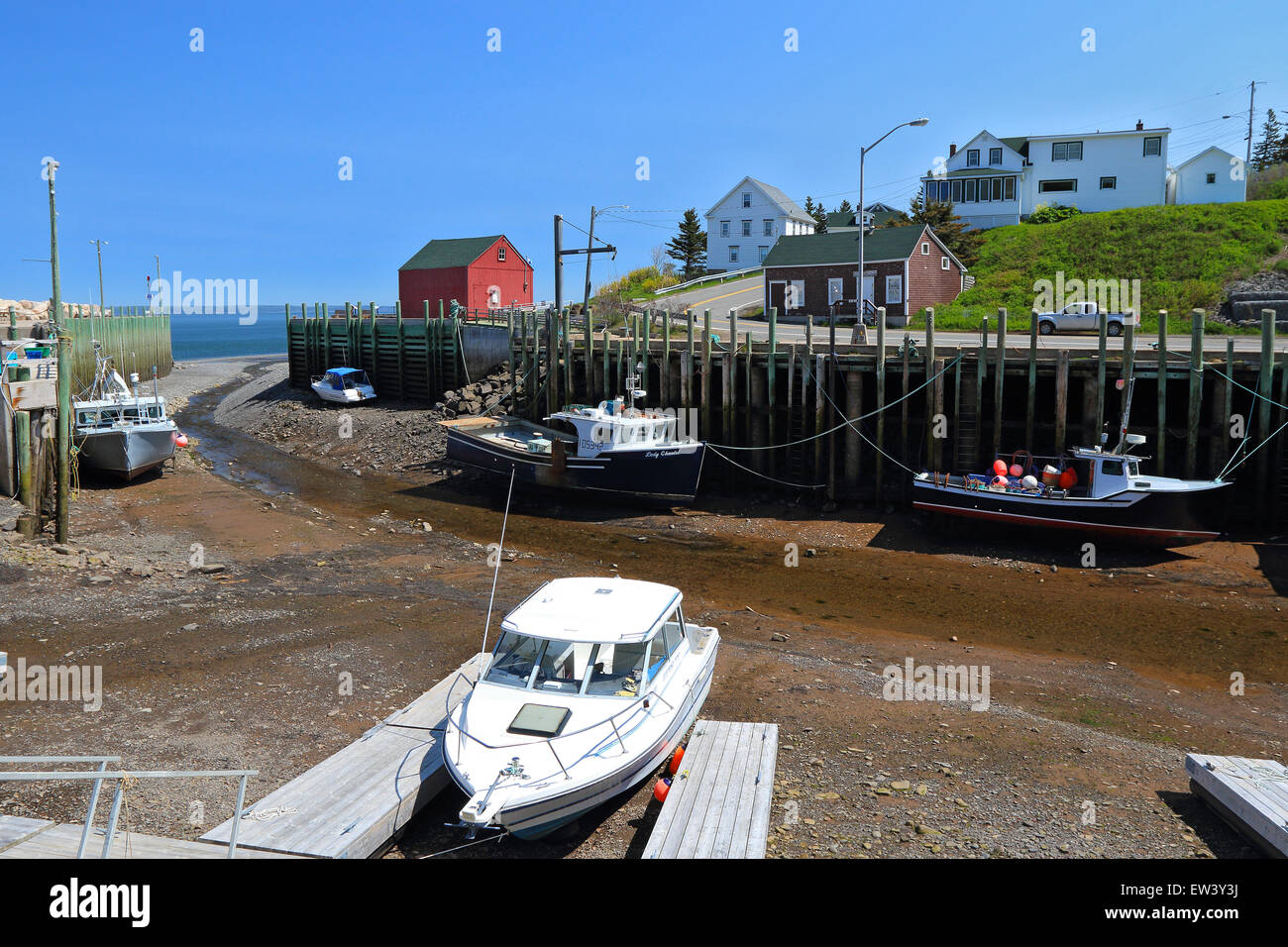 Baia di Fundy, Nova Scotia, Canada. Hall il porto del villaggio di pescatori con la bassa marea con barche da pesca sul fango. Padiglioni del porto. Foto Stock
