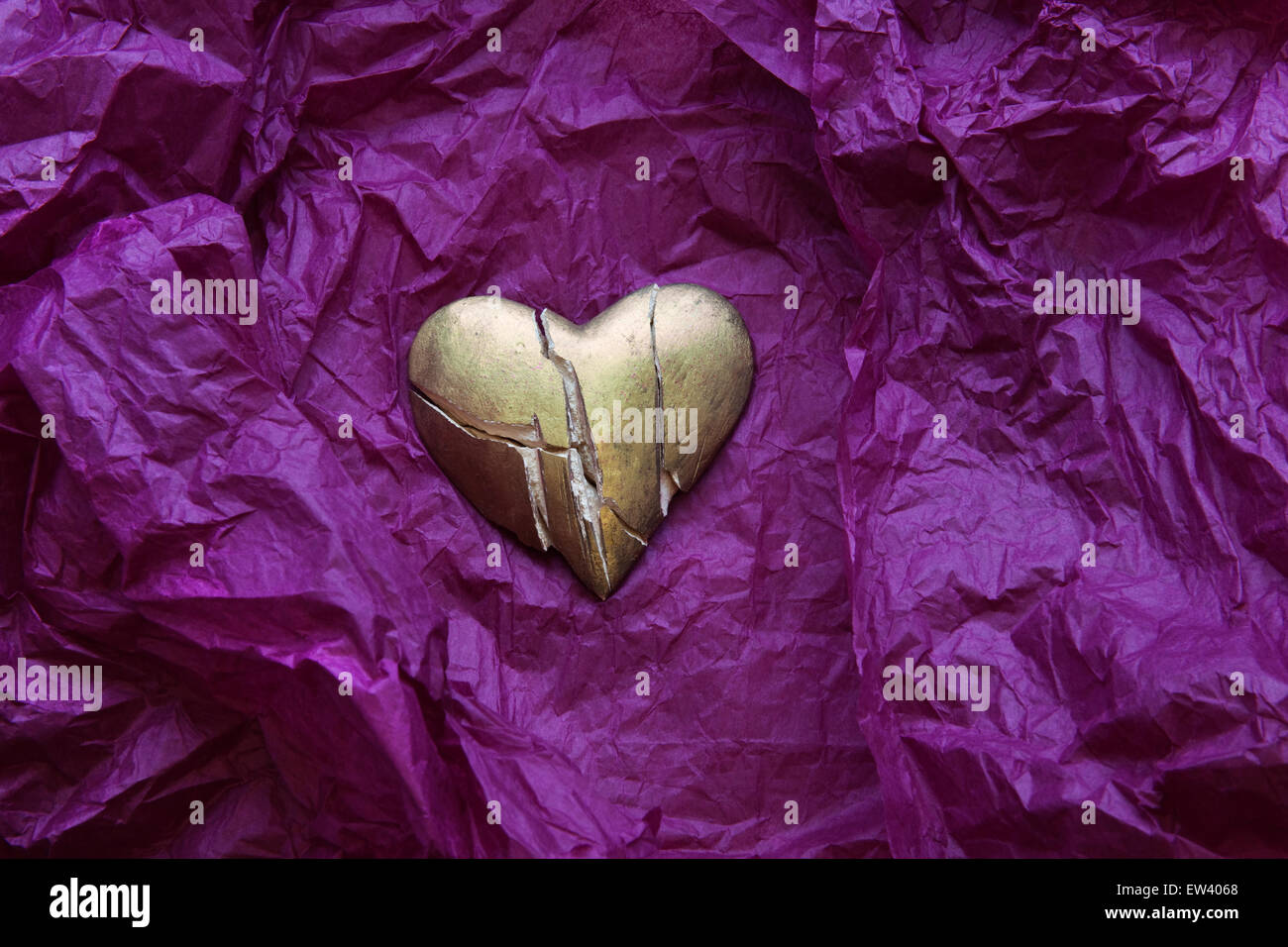 In frantumi, Oro dipinta sul cuore accartocciata viola carta tessuto. Foto Stock