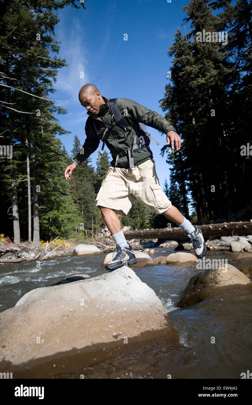 African American uomo Cupido Alexander salta lungo torrente nel Cascade Mountains Oregon. Foto Stock