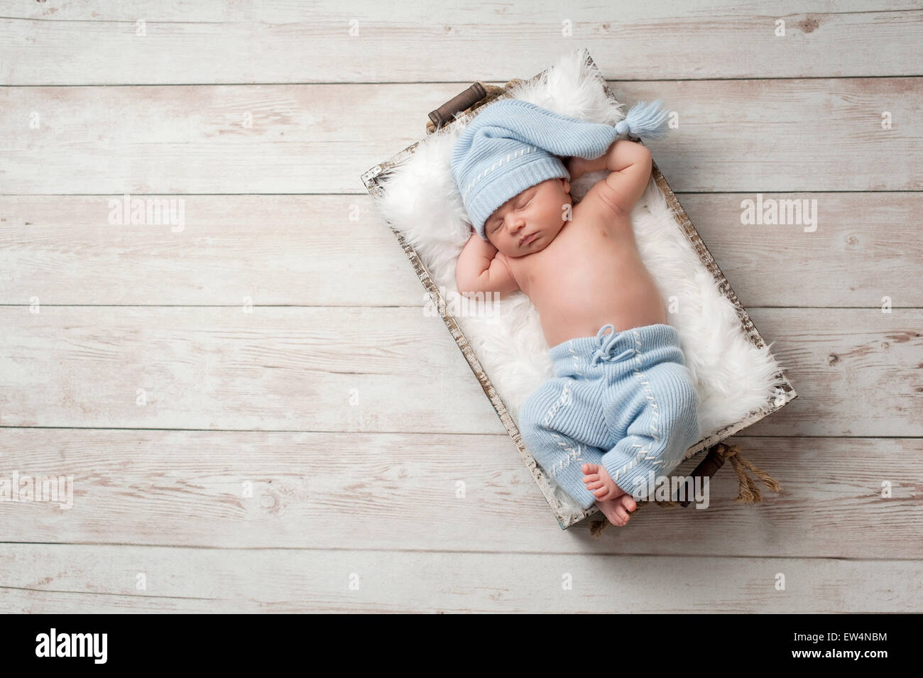 Neonato dormire in una cassa di legno su un dipinto di bianco con pavimento in legno. Indossa la luce blu, riutilizzato pigiama con un scollatu Foto Stock