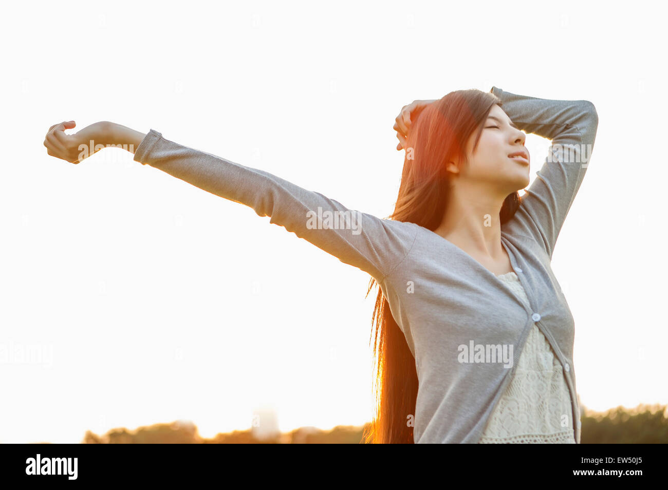 Giovane donna chiudendo gli occhi con le braccia aperte Foto Stock