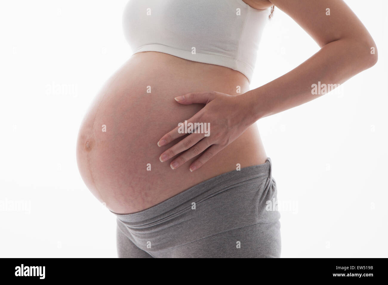 Donna incinta in piedi con le mani sul ventre, Foto Stock