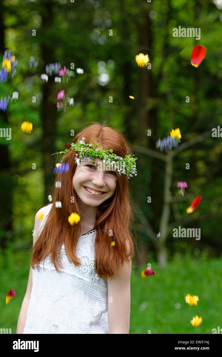 Fiore bambino, ragazza con ghirlanda di fiori nei capelli, fiori piovono Foto Stock