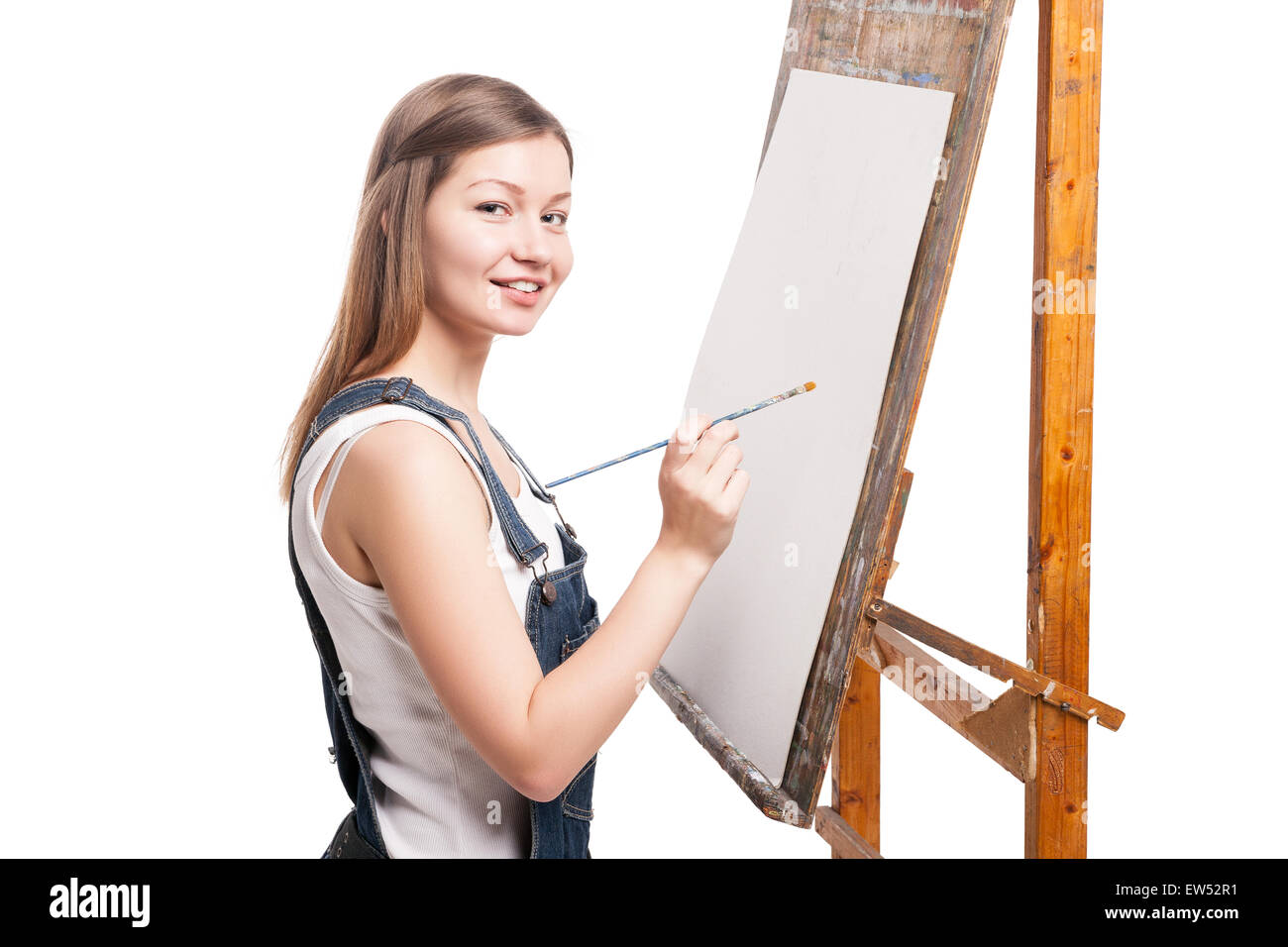 Giovane donna sorridente pittore con il pennello permanente al cavalletto Foto Stock