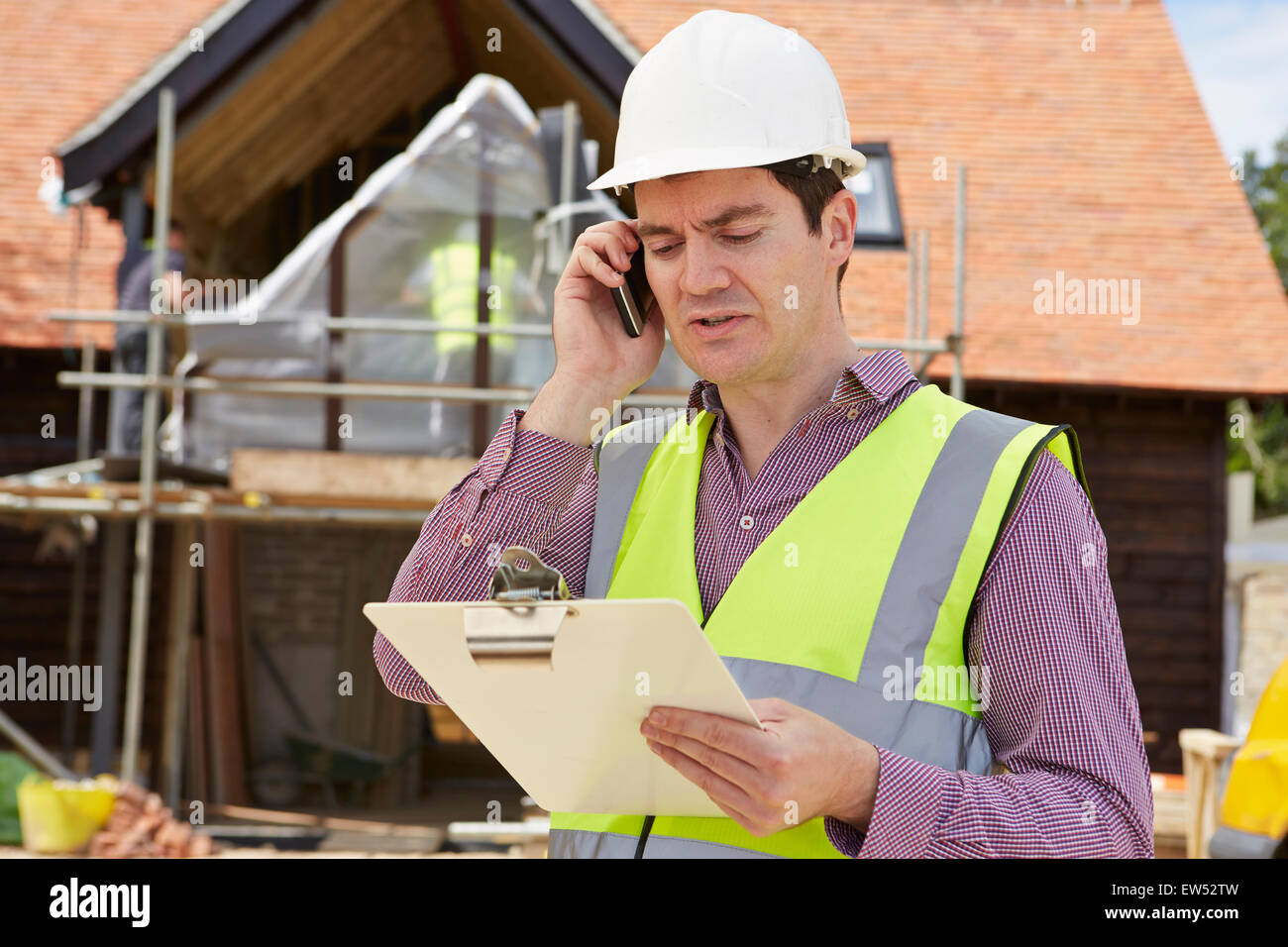 Architetto in cantiere utilizzando il telefono cellulare Foto Stock