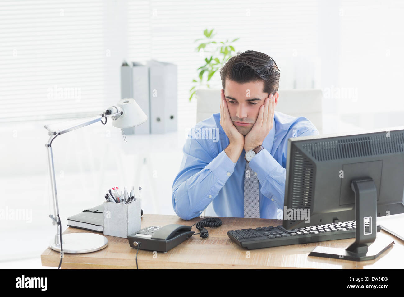 Imprenditore triste seduto alla sua scrivania Foto Stock