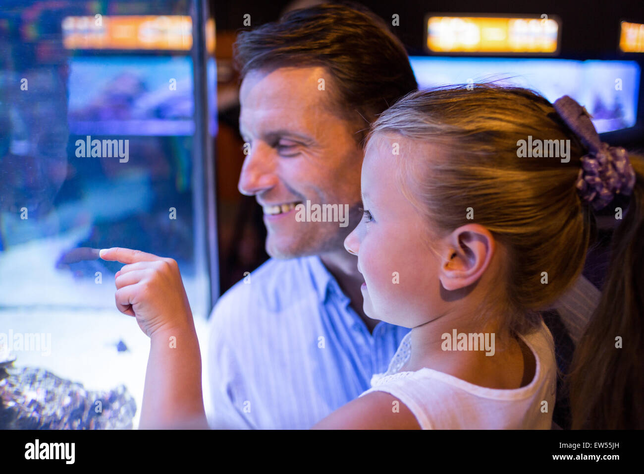 Figlia lookingand padre guardando i pesci nel serbatoio Foto Stock