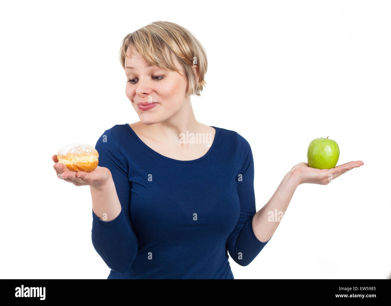 Giovane donna in possesso di una ciambella e un apple, attratti dalla la ciambella, isolato su bianco Foto Stock