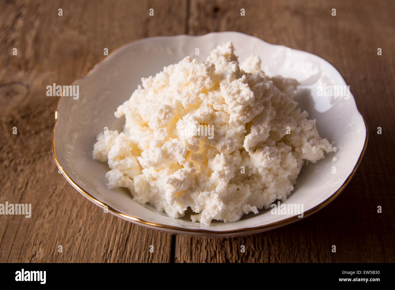 Cottage cheese in bianco coppa sopra rustico sfondo di legno vicino fino Foto Stock