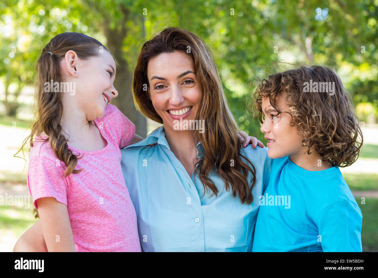 Madre e bambini sorridenti e baciare in un parco Foto Stock