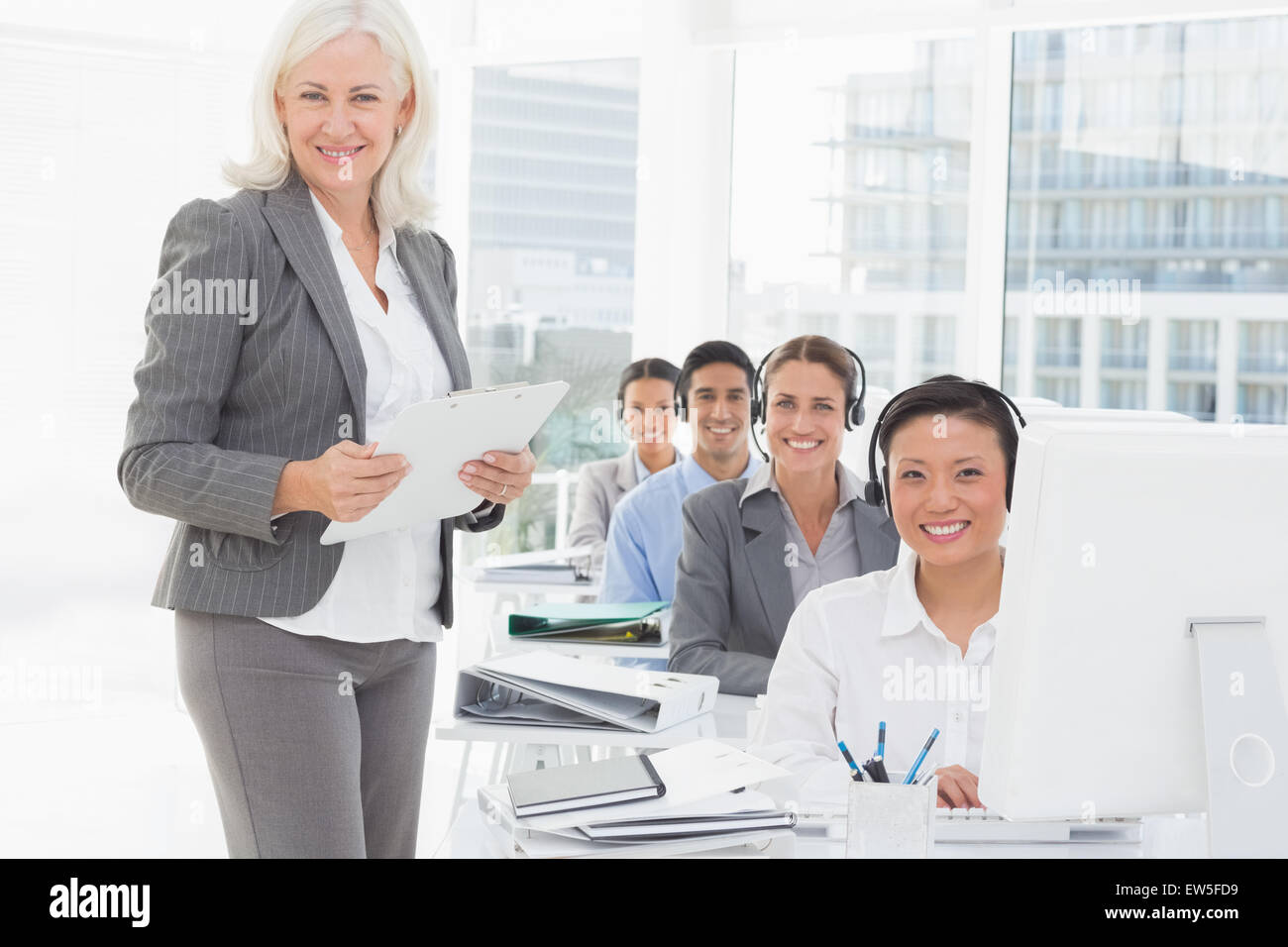 Sorridente imprenditrice guardando la fotocamera mentre il team di lavoro tramite il computer Foto Stock