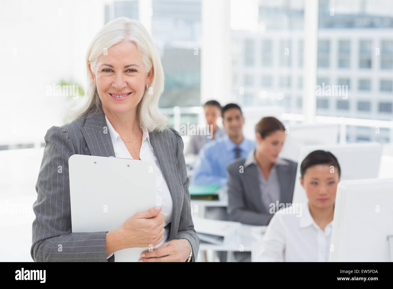 Sorridente imprenditrice guardando la fotocamera mentre il team di lavoro tramite il computer Foto Stock