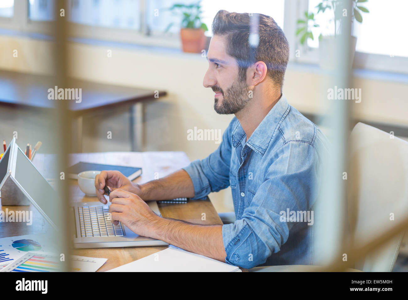 Imprenditore sorridente lavorando sul computer portatile Foto Stock