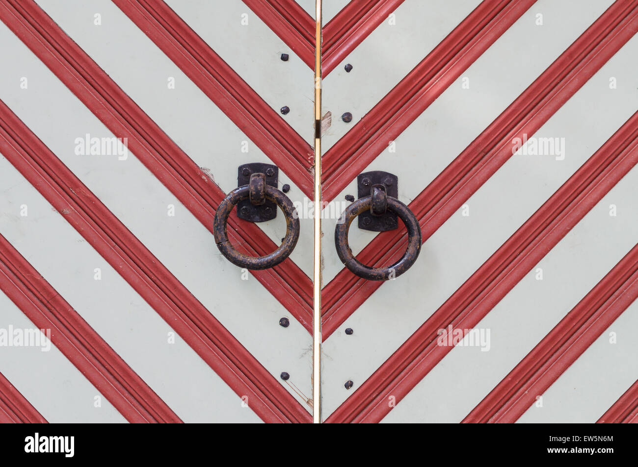 Vecchio di legno rosso-bianco striato con gate di metallo arrugginito gestisce Foto Stock