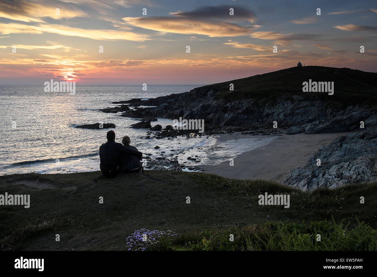 Un giovane guardando un tramonto spettacolare sulla costa a Newquay in Cornovaglia. Foto Stock