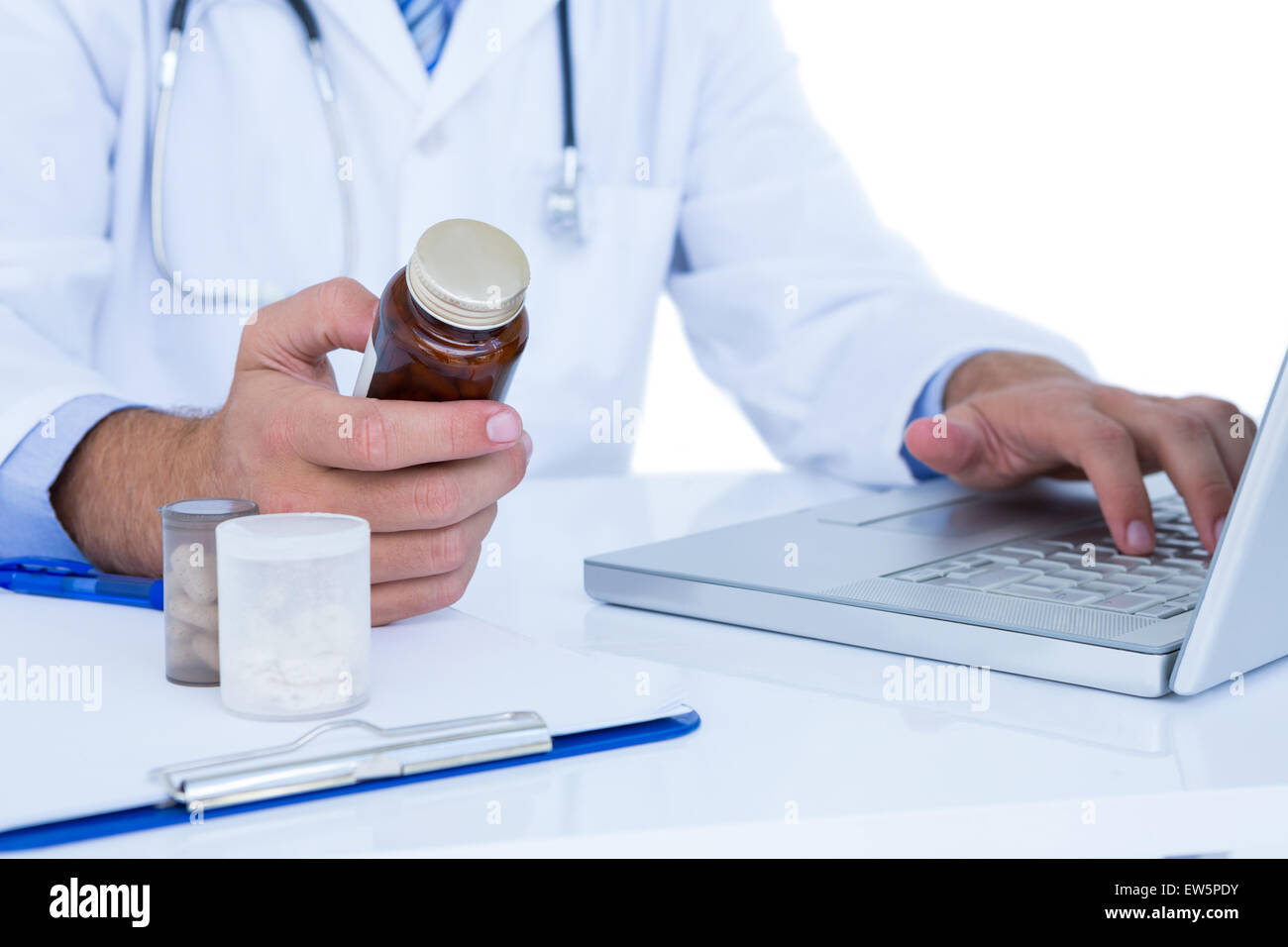 Un medico in possesso di una medicina durante la digitazione su un computer portatile Foto Stock
